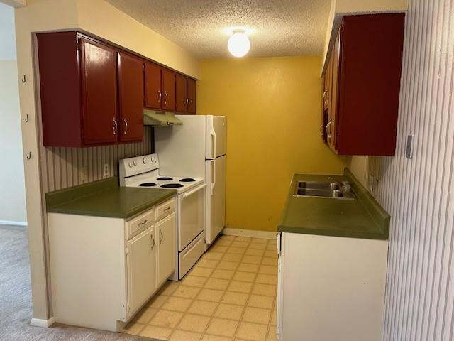 3600 Gabriel Ave Unit 303, Parsons, KS 67357 - kitchen featuring white range with electric stovetop, under cabinet range hood, dark countertops, a textured ceiling, and white cabinets