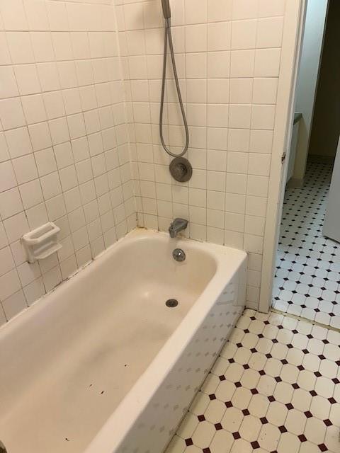 3600 Gabriel Ave Unit 303, Parsons, KS 67357 - bathroom featuring tile patterned floors, shower / washtub combination, and tile walls