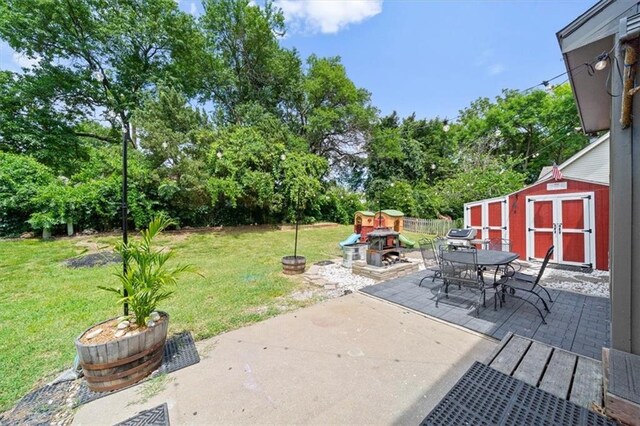 14522 W 61st St, Shawnee, KS 66216 - view of patio with outdoor dining area, a storage unit, and view of wooded area