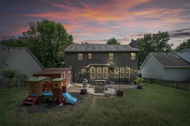 14522 W 61st St, Shawnee, KS 66216 - back of property at dusk featuring a patio area, a fire pit, board and batten siding, a fenced backyard, and a chimney