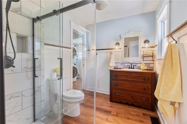 217 W 9th St, Ottawa, KS 66067 - full bathroom with stacked washer / dryer, wood finished floors, a shower stall, and vanity