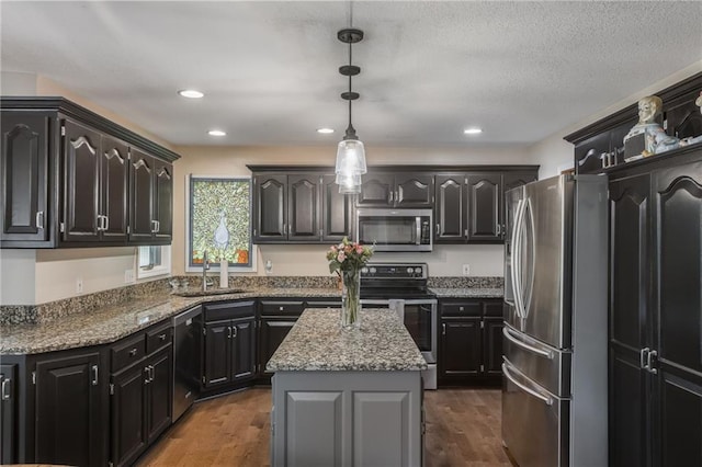 4902 Corinth Dr, Saint Joseph, MO 64506 - kitchen with appliances with stainless steel finishes, a center island, stone countertops, dark wood-type flooring, and pendant lighting