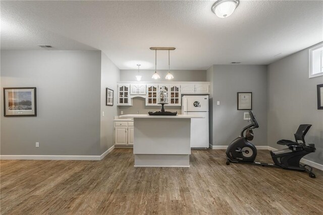 4902 Corinth Dr, Saint Joseph, MO 64506 - kitchen featuring freestanding refrigerator, white cabinetry, wood finished floors, a center island, and a textured ceiling