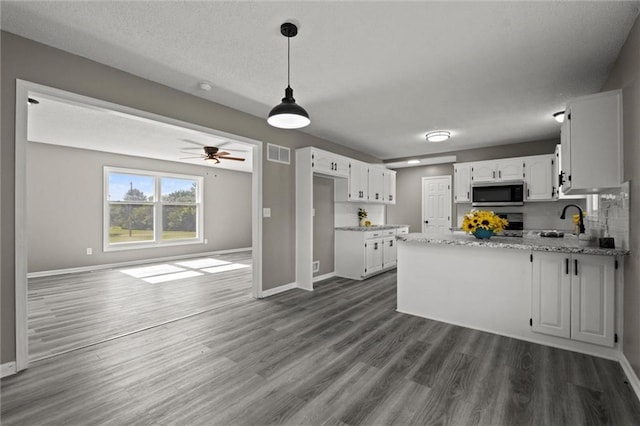 23404 Waverly Rd, Spring Hill, KS 66083 - kitchen featuring stainless steel microwave, a peninsula, white cabinetry, dark wood-style floors, and open floor plan