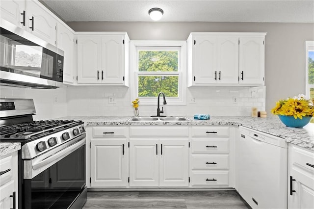 23404 Waverly Rd, Spring Hill, KS 66083 - kitchen with appliances with stainless steel finishes, plenty of natural light, white cabinets, decorative backsplash, and a textured ceiling