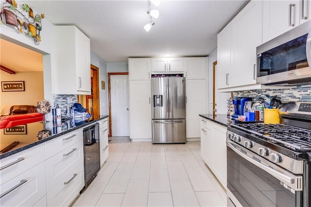 601 W 14th St, Pleasanton, KS 66075 - kitchen with stainless steel appliances, decorative backsplash, white cabinets, dark stone countertops, and beverage cooler