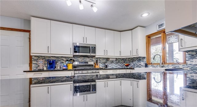 601 W 14th St, Pleasanton, KS 66075 - kitchen featuring stainless steel appliances, white cabinetry, backsplash, a textured ceiling, and recessed lighting