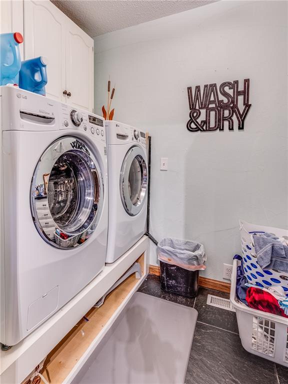 601 W 14th St, Pleasanton, KS 66075 - laundry room featuring cabinet space, washing machine and dryer, and a textured ceiling