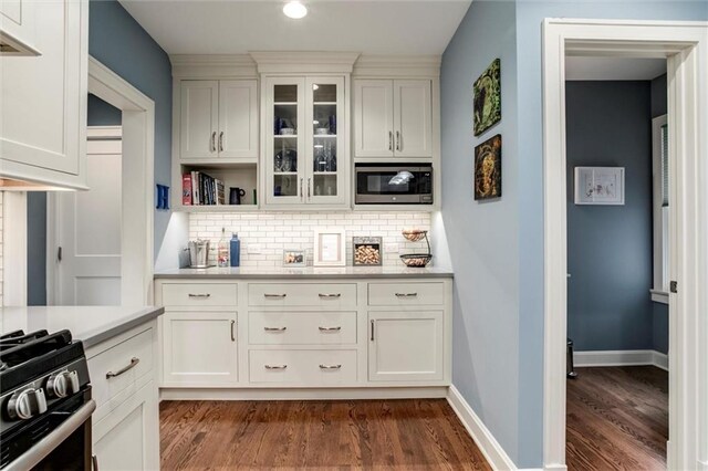 6033 Central St, Kansas City, MO 64113 - kitchen featuring stainless steel microwave, dark wood-style flooring, decorative backsplash, light countertops, and gas range