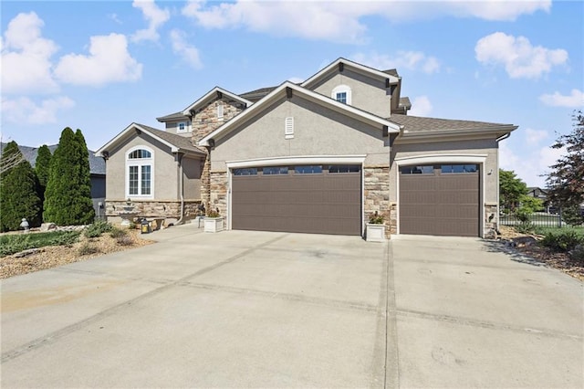 1401 Spurlock Cv, Raymore, MO 64083 - view of front facade with stone siding, an attached garage, concrete driveway, and stucco siding