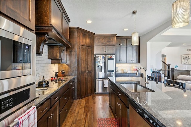 1401 Spurlock Cv, Raymore, MO 64083 - kitchen featuring stainless steel appliances, decorative light fixtures, dark wood-style floors, dark stone counters, and recessed lighting