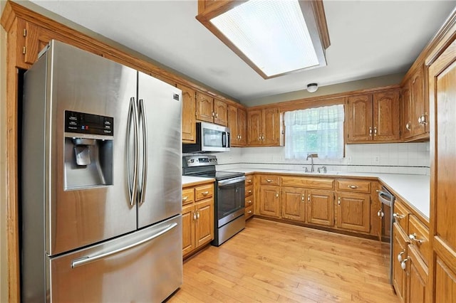 802 S Morgan Dr, Peculiar, MO 64078 - kitchen featuring stainless steel appliances, light wood-style flooring, light countertops, brown cabinetry, and decorative backsplash