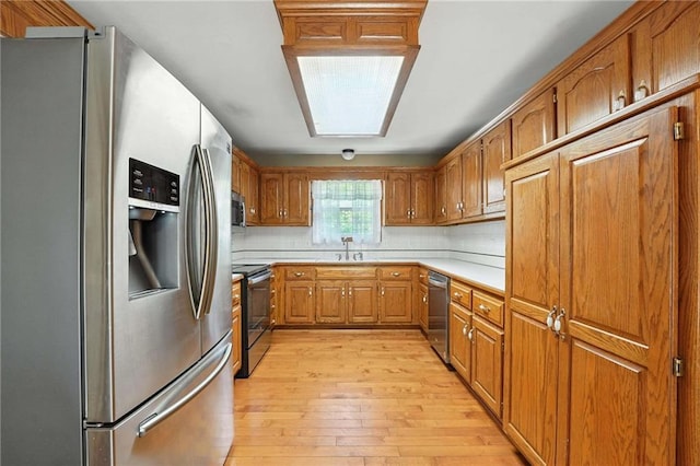 802 S Morgan Dr, Peculiar, MO 64078 - kitchen featuring stainless steel appliances, brown cabinets, light wood-style flooring, light countertops, and tasteful backsplash