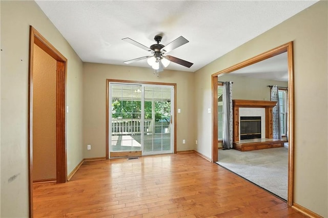 802 S Morgan Dr, Peculiar, MO 64078 - spare room featuring light wood-style floors, a ceiling fan, and a glass covered fireplace