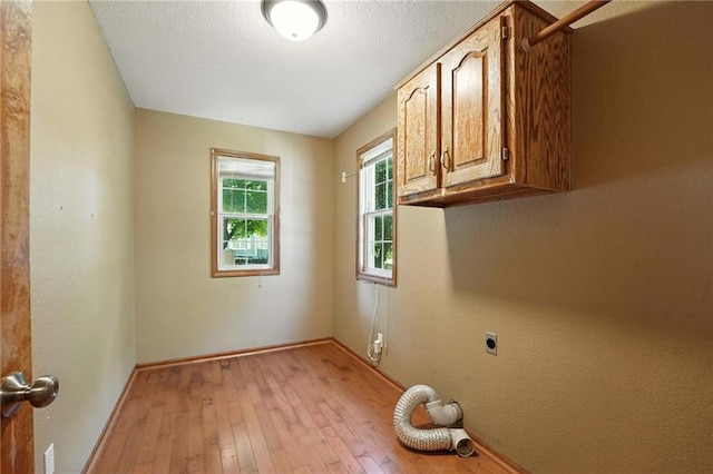 802 S Morgan Dr, Peculiar, MO 64078 - washroom featuring electric dryer hookup, cabinet space, light wood-style flooring, and a textured ceiling