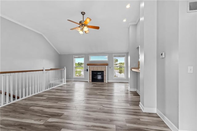 13785 E Nelson Rd, Nevada, MO 64772 - unfurnished living room with a ceiling fan, ornamental molding, wood finished floors, vaulted ceiling, and a tiled fireplace