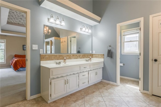 2621 SE 5th St, Lees Summit, MO 64063 - ensuite bathroom featuring double vanity, healthy amount of natural light, tile patterned floors, and tasteful backsplash