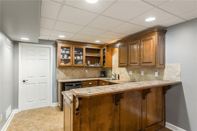 2621 SE 5th St, Lees Summit, MO 64063 - kitchen featuring a breakfast bar, brown cabinets, light countertops, a peninsula, and glass insert cabinets