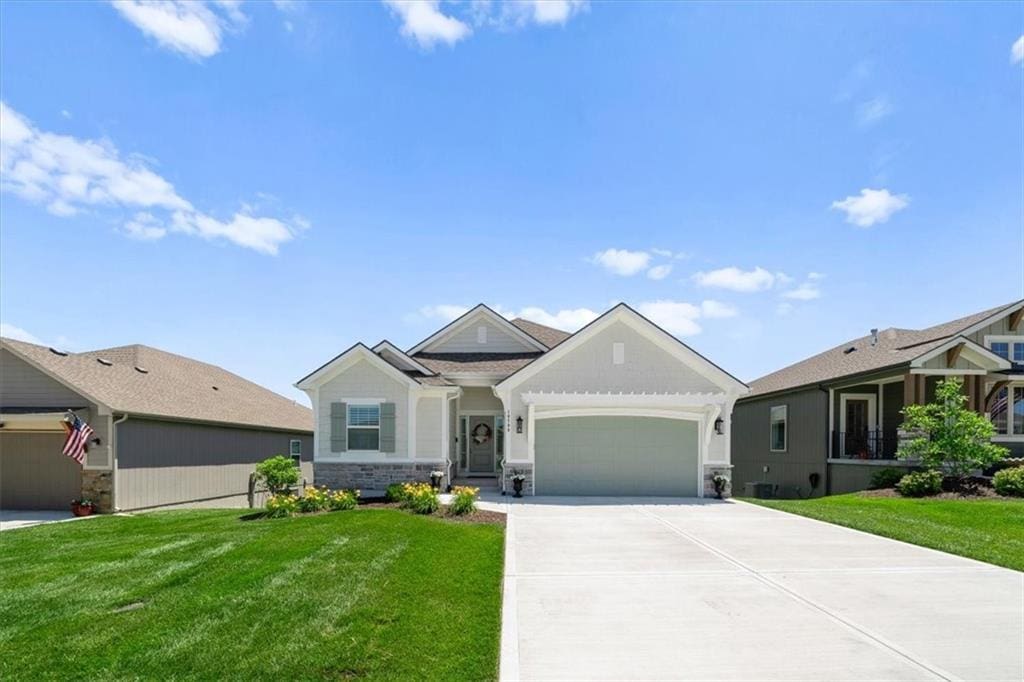 10709 N Bell St, Kansas City, MO 64155 - view of front facade with an attached garage, a front yard, stone siding, and concrete driveway