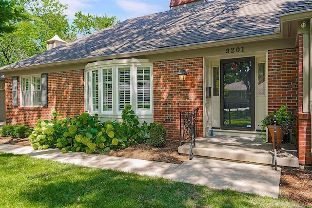 9201 Ensley Ln, Leawood, KS 66206 - property entrance featuring brick siding, roof with shingles, and a chimney
