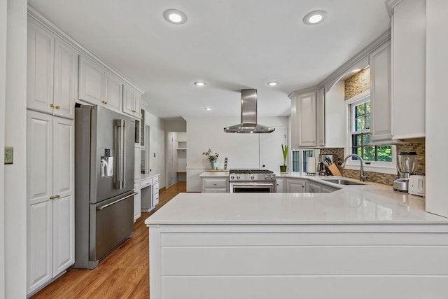 9201 Ensley Ln, Leawood, KS 66206 - kitchen with premium appliances, wall chimney range hood, a peninsula, light countertops, and recessed lighting
