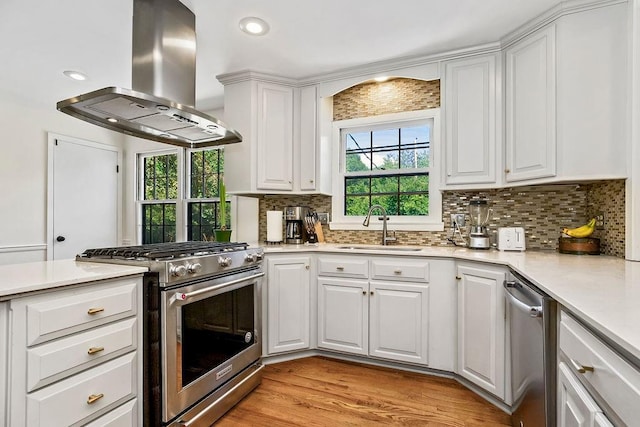 9201 Ensley Ln, Leawood, KS 66206 - kitchen featuring island exhaust hood, appliances with stainless steel finishes, decorative backsplash, light countertops, and white cabinetry