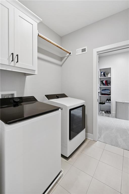 9260 Saddletop St, Lenexa, KS 66227 - laundry area featuring cabinet space, washing machine and dryer, light tile patterned floors, and light carpet
