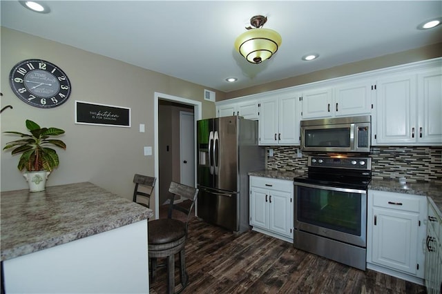 1005 Hunters Rd, Blue Springs, MO 64014 - kitchen featuring stainless steel appliances, dark wood finished floors, backsplash, white cabinetry, and recessed lighting