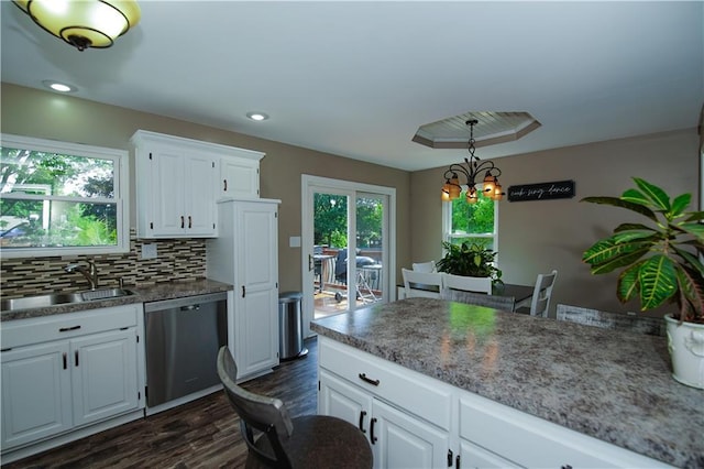 1005 Hunters Rd, Blue Springs, MO 64014 - kitchen with stainless steel dishwasher, dark wood finished floors, white cabinets, decorative backsplash, and a chandelier