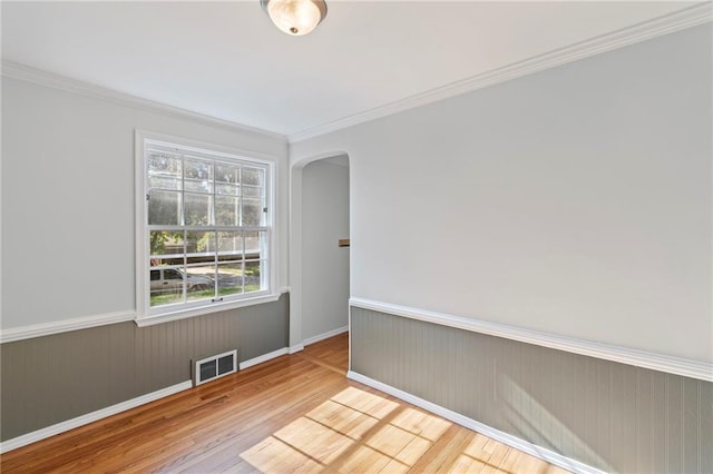 7712 Mcgee St, Kansas City, MO 64114 - spare room with arched walkways, wainscoting, wood finished floors, and ornamental molding