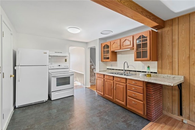 7712 Mcgee St, Kansas City, MO 64114 - kitchen featuring white appliances, custom range hood, arched walkways, backsplash, and brown cabinetry