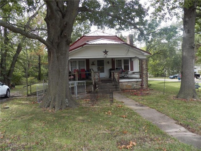 514 Front St, Prescott, KS 66767 - bungalow with covered porch, a front lawn, and a chimney