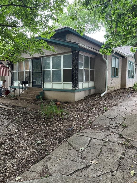 1906 S Willow Ave, Independence, MO 64052 - view of side of home with a sunroom, entry steps, and stucco siding