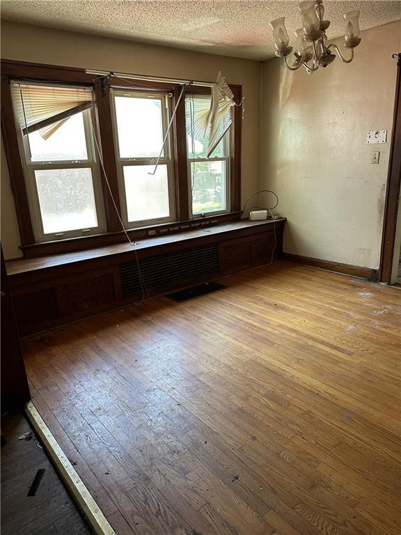 1906 S Willow Ave, Independence, MO 64052 - empty room featuring hardwood / wood-style flooring, a chandelier, and a textured ceiling