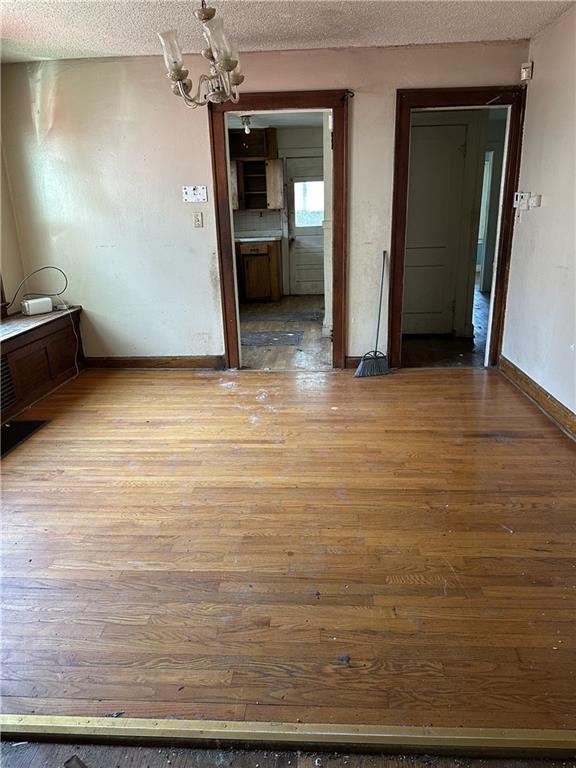 1906 S Willow Ave, Independence, MO 64052 - unfurnished dining area featuring wood finished floors, a textured ceiling, and a chandelier