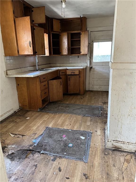 1906 S Willow Ave, Independence, MO 64052 - kitchen with light wood-type flooring, brown cabinetry, open shelves, light countertops, and tasteful backsplash