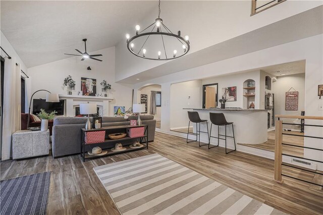 792 195th St, Fort Scott, KS 66701 - living room with arched walkways, light wood-style floors, high vaulted ceiling, a ceiling fan, and a chandelier