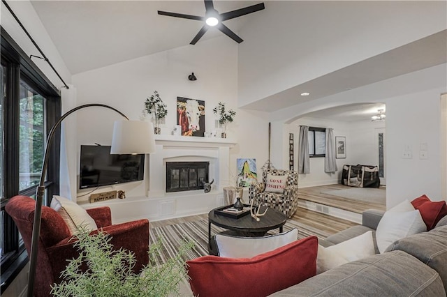 792 195th St, Fort Scott, KS 66701 - living room featuring arched walkways, a ceiling fan, a glass covered fireplace, high vaulted ceiling, and wood finished floors