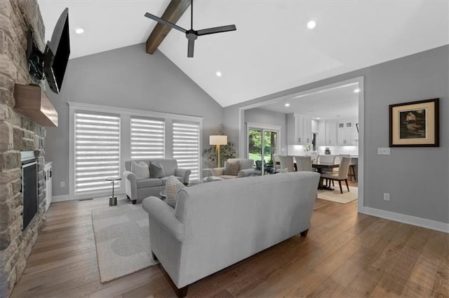 13 Tahoma Rdg, Lake Winnebago, MO 64034 - living area featuring a ceiling fan, beam ceiling, wood finished floors, a stone fireplace, and high vaulted ceiling