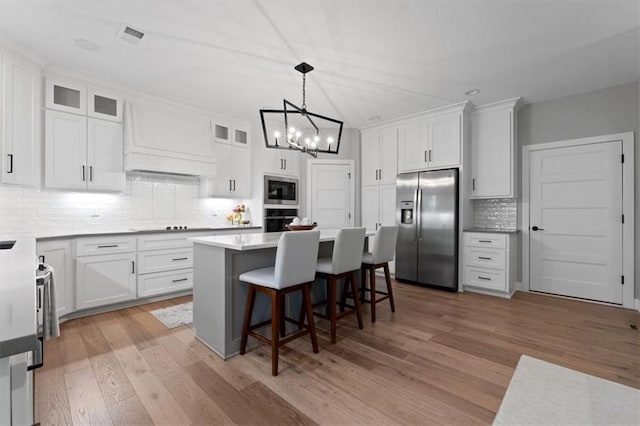 13 Tahoma Rdg, Lake Winnebago, MO 64034 - kitchen with stainless steel appliances, a chandelier, white cabinets, tasteful backsplash, and a kitchen island