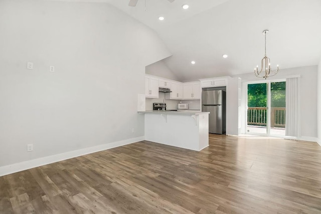 4724 E 135th Ct, Grandview, MO 64030 - kitchen featuring freestanding refrigerator, a peninsula, a breakfast bar area, white cabinets, and range