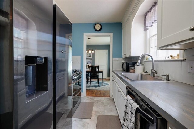 1421 W 28th Ter, Independence, MO 64052 - kitchen featuring appliances with stainless steel finishes, a chandelier, white cabinetry, and light countertops
