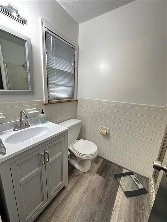 12913 E 41st St S, Independence, MO 64055 - full bathroom featuring tile walls, a textured ceiling, vanity, wood finished floors, and a wainscoted wall