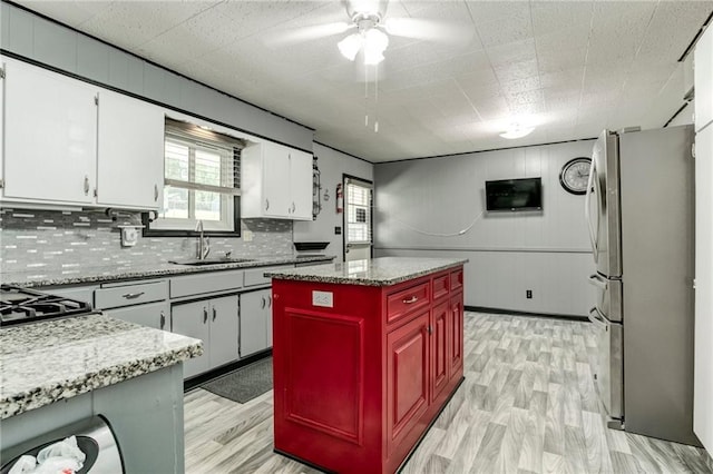 815 N 63rd St, Kansas City, KS 66102 - kitchen with freestanding refrigerator, a ceiling fan, decorative backsplash, light wood-style floors, and white cabinetry