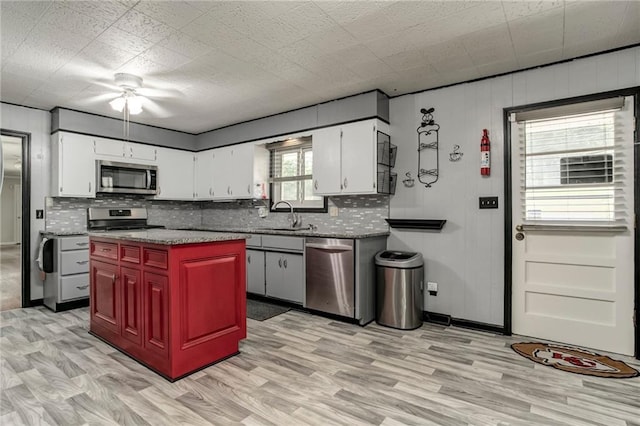 815 N 63rd St, Kansas City, KS 66102 - kitchen featuring stainless steel appliances, backsplash, white cabinets, and light wood-style floors