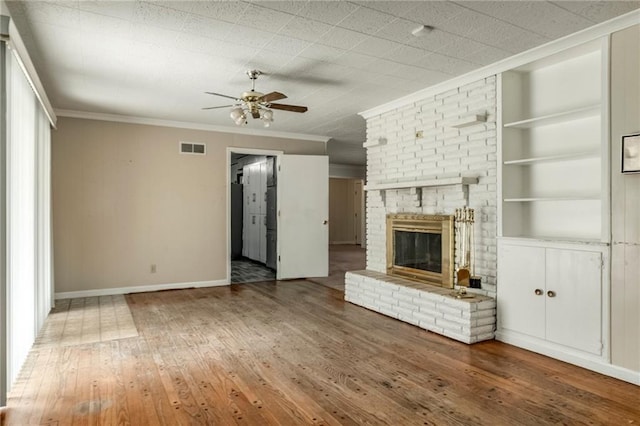 815 N 63rd St, Kansas City, KS 66102 - unfurnished living room with built in shelves, ceiling fan, crown molding, a fireplace, and hardwood / wood-style floors