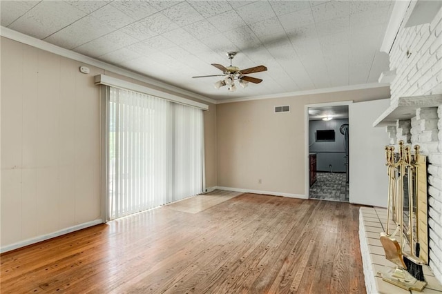 815 N 63rd St, Kansas City, KS 66102 - unfurnished living room featuring hardwood / wood-style flooring, ceiling fan, plenty of natural light, crown molding, and a large fireplace