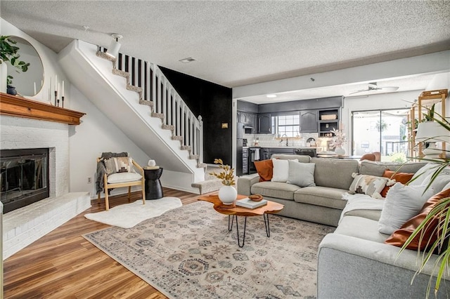 512 NE Brookwood Cir Unit A, Blue Springs, MO 64014 - living area with stairway, a textured ceiling, a brick fireplace, and light wood-type flooring