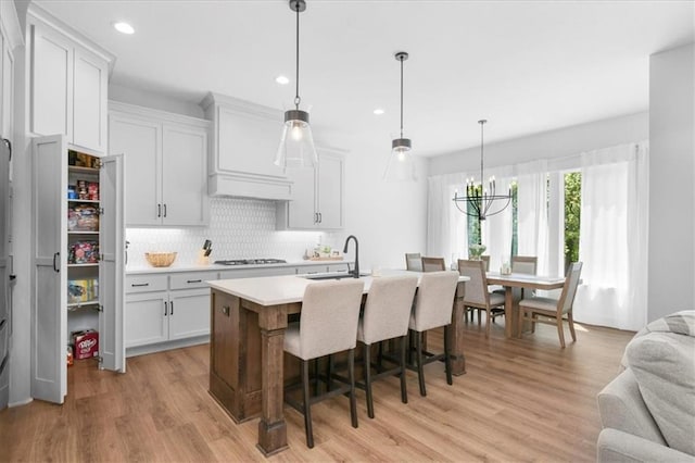 1161 SW Whitby Dr, Lees Summit, MO 64083 - kitchen featuring light countertops, backsplash, light wood-style floors, gas stovetop, and custom exhaust hood
