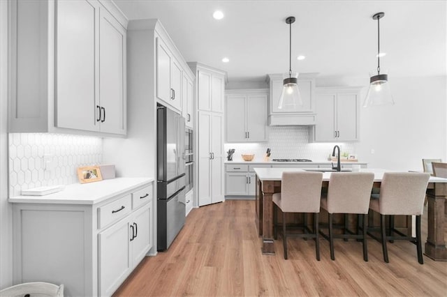 1161 SW Whitby Dr, Lees Summit, MO 64083 - kitchen with stainless steel appliances, custom range hood, decorative backsplash, a breakfast bar, and recessed lighting